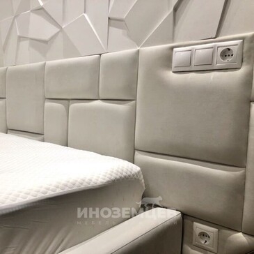 Мягкое изголовье двуспальной кровати со встроенными розетками и выключателями