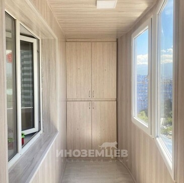 Встроенный шкаф в светлом дереве в торцевой части балкона, вид спереди