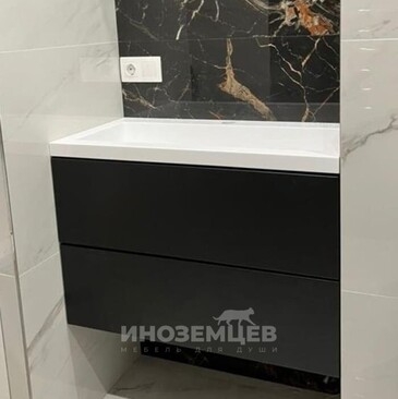 Черная подвесная тумба в ванной комнате с белой раковиной и выдвижными ящиками