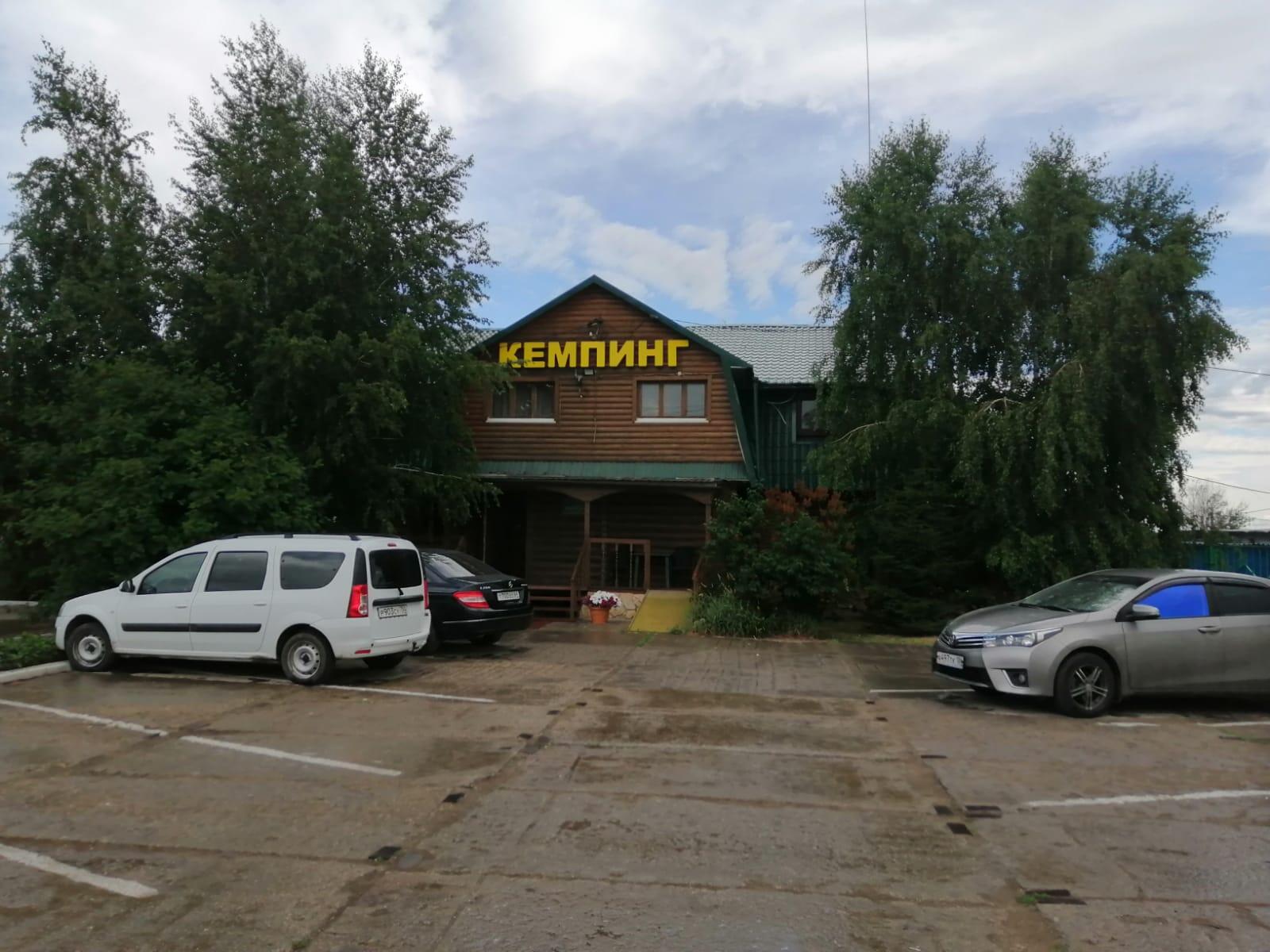Гостевой дом «Нептун»: деревянный сруб с вывеской «Кемпинг», парковка перед входом