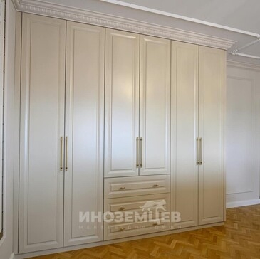 Светлый распашной шкаф в классическом стиле с золотистыми ручками в интерьере спальни