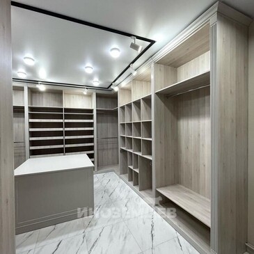 Современная открытая гардеробная комната с островком и полками светлого дерева
