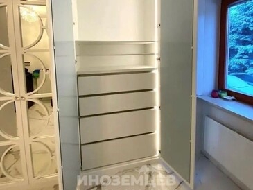 Вид на внутреннее наполнение белого распашного шкафа с зеркальными дверями