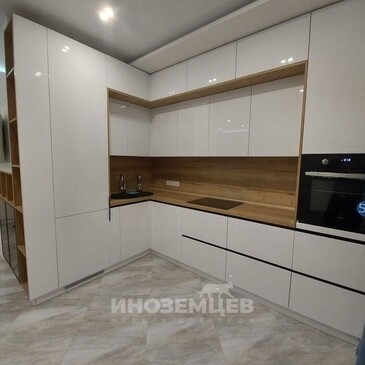 Современная угловая кухня с белыми фасадами и деревянной столешницей