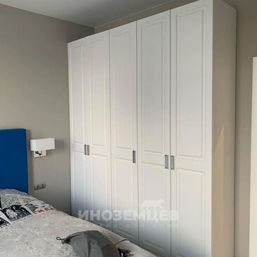 Угловой белый шкаф с фрезеровкой и ручками в классическом стиле в детской комнате мальчика