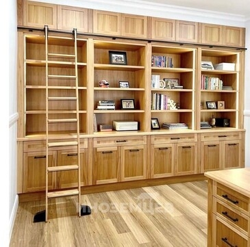 Большой деревянный книжный шкаф на заказ с полками и передвижной лестницей в интерьере