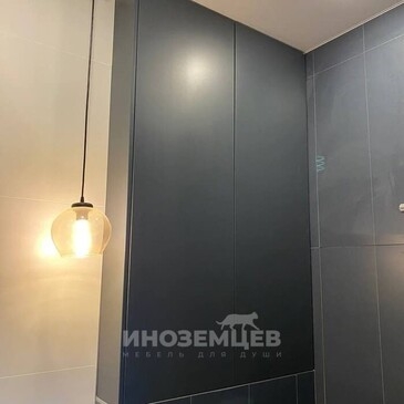 Интерьер совмещенного санузла с черным шкафом над инсталляцией и подвесным светильником