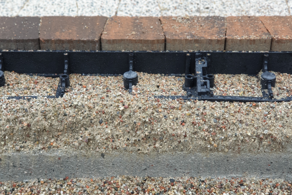 Бордюрный камень установлен на бетонное основание — правильная фиксация края тротуарной плитки