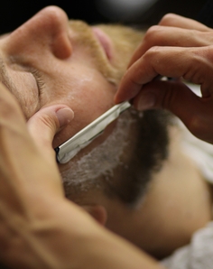 Barber performing a hot towel straight razor shave in Prague