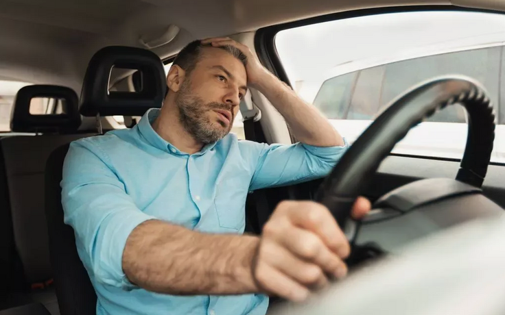 расстроенный водитель сидит за рулем автомобиля