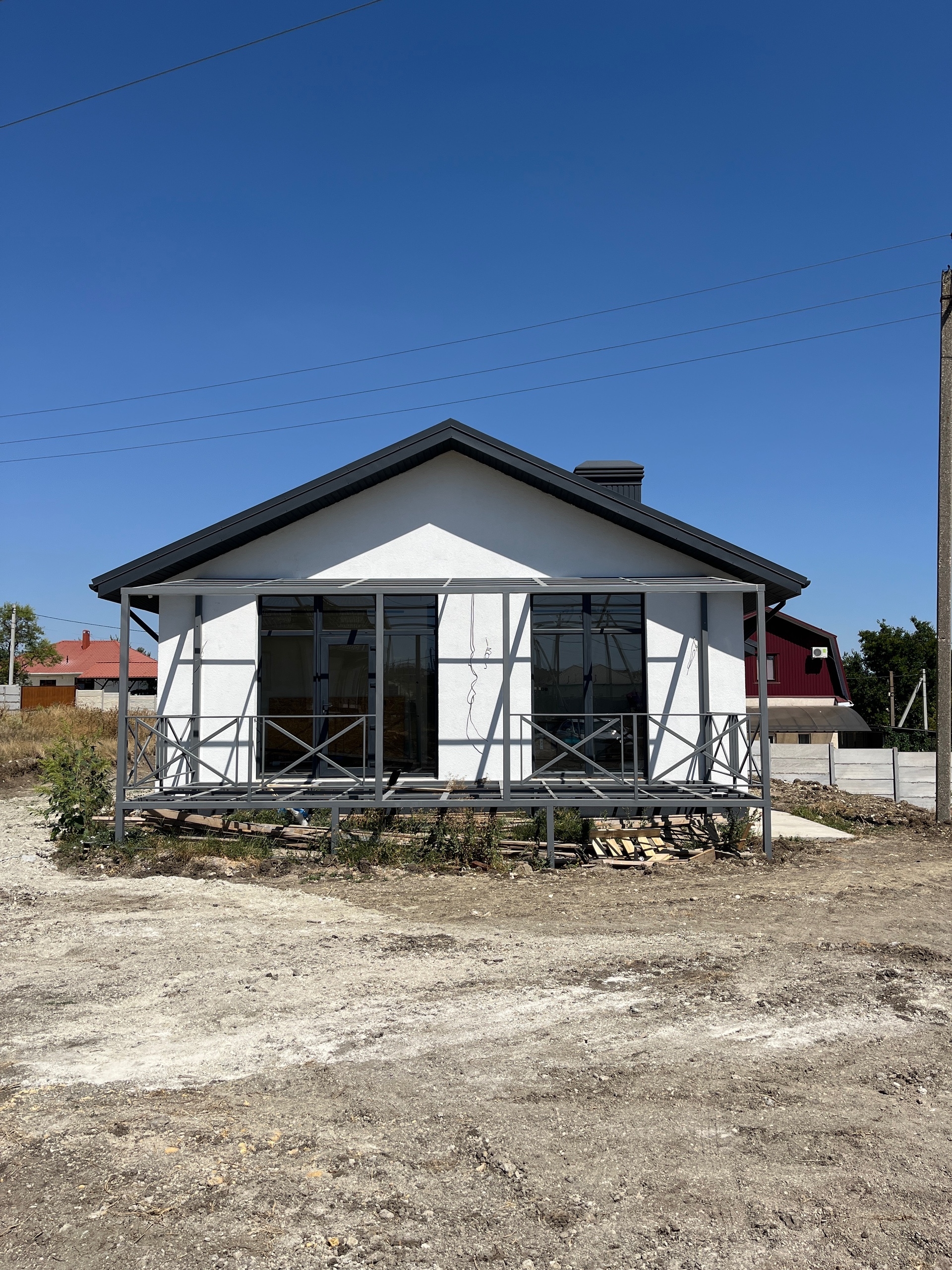 Фото дома с белым фасадом, двухтактной крышей и верандой