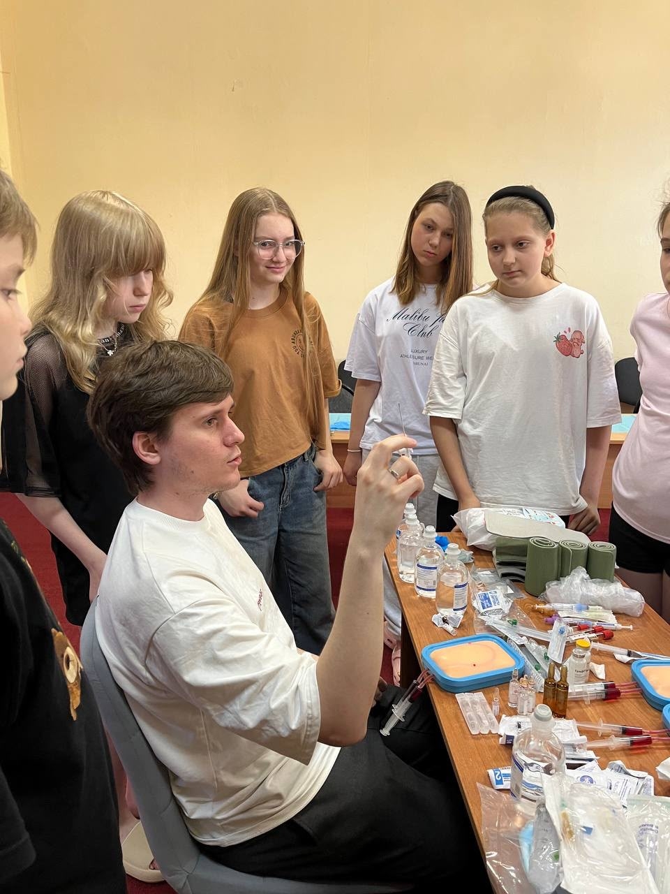Наставник показывает медицинские инструменты школьникам на практикуме в зимнем медицинском лагере Се