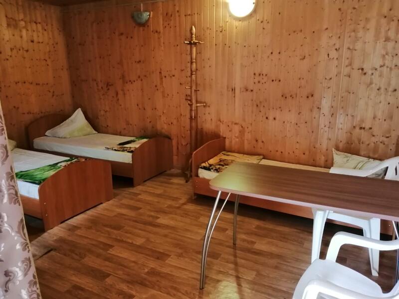 Летний домик внутри: кровати, стол и пластиковые кресла