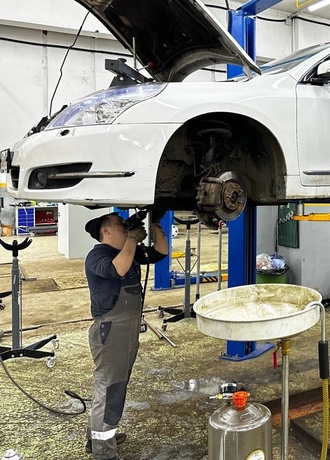 Механник ремонтирует АКПП на подьемнике