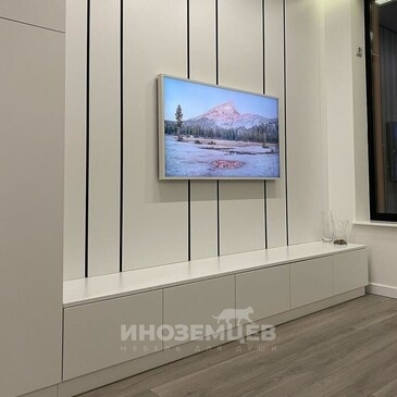 Белая длинная тумба под телевизор и высокий шкаф в интерьере гостиной